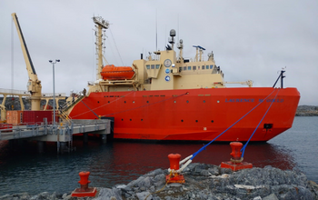 Large orange ship tied up next to a dock